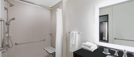 A modern bathroom with a shower, a bench, a sink, and a mirror.