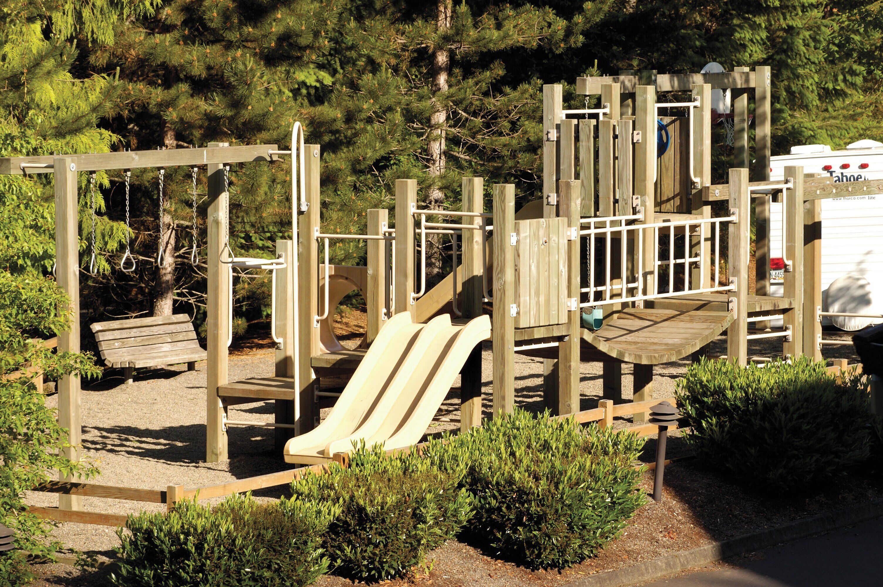Un parque infantil con tobogán, estructuras para escalar y un banco.