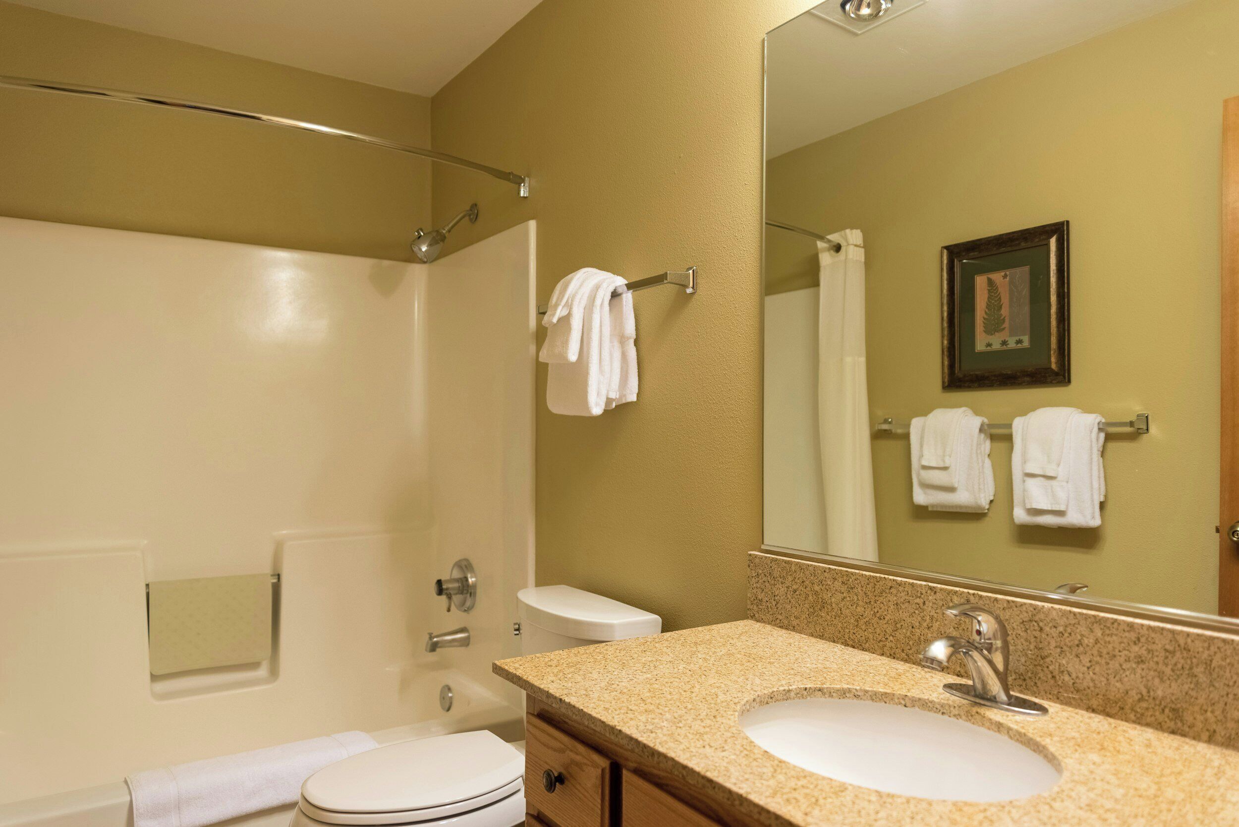 Une salle de bain équipée d’une douche, de toilettes, d’un lavabo et d’un grand miroir.