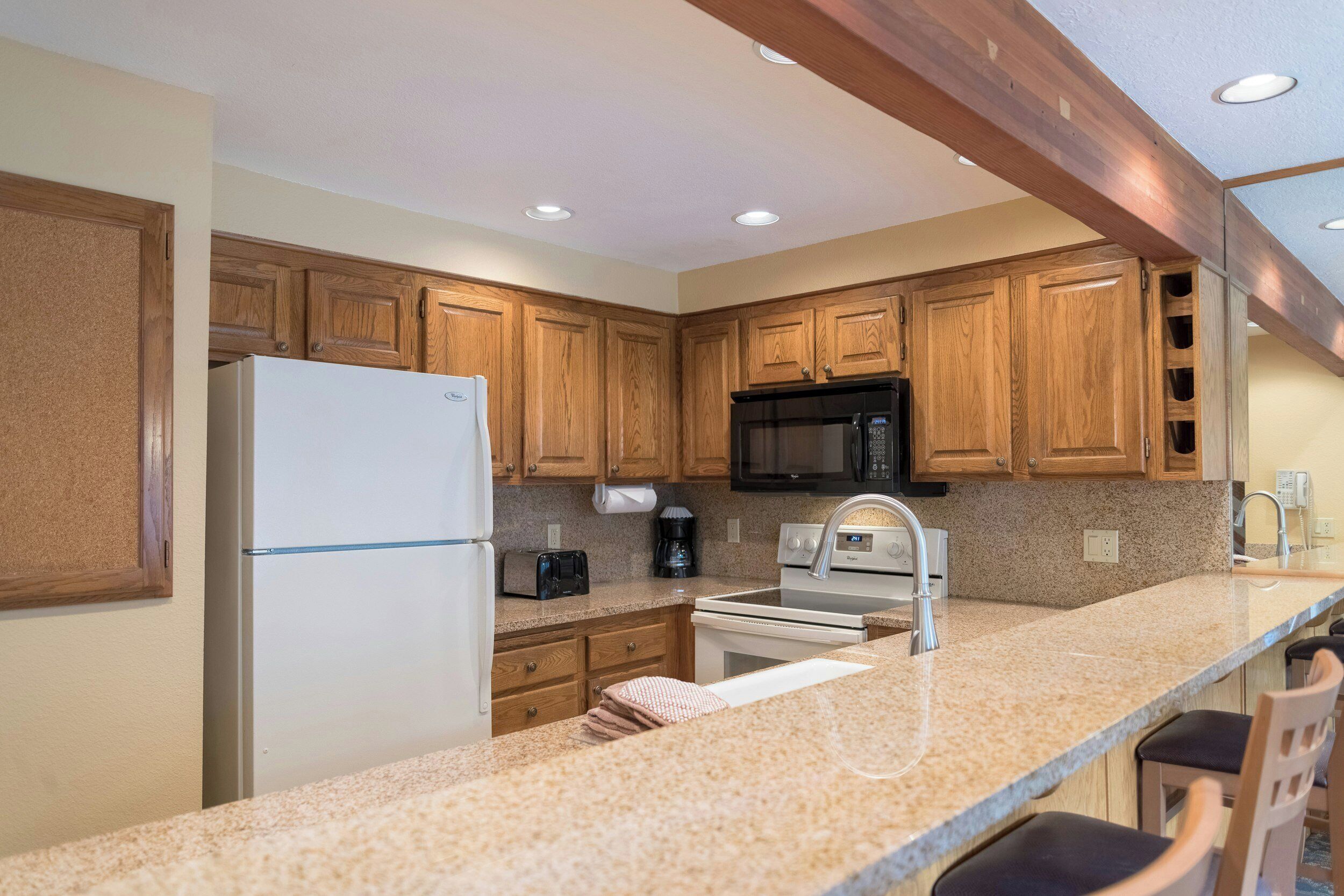 A kitchen with wooden cabinets, a refrigerator, a microwave, a toaster, and a sink.