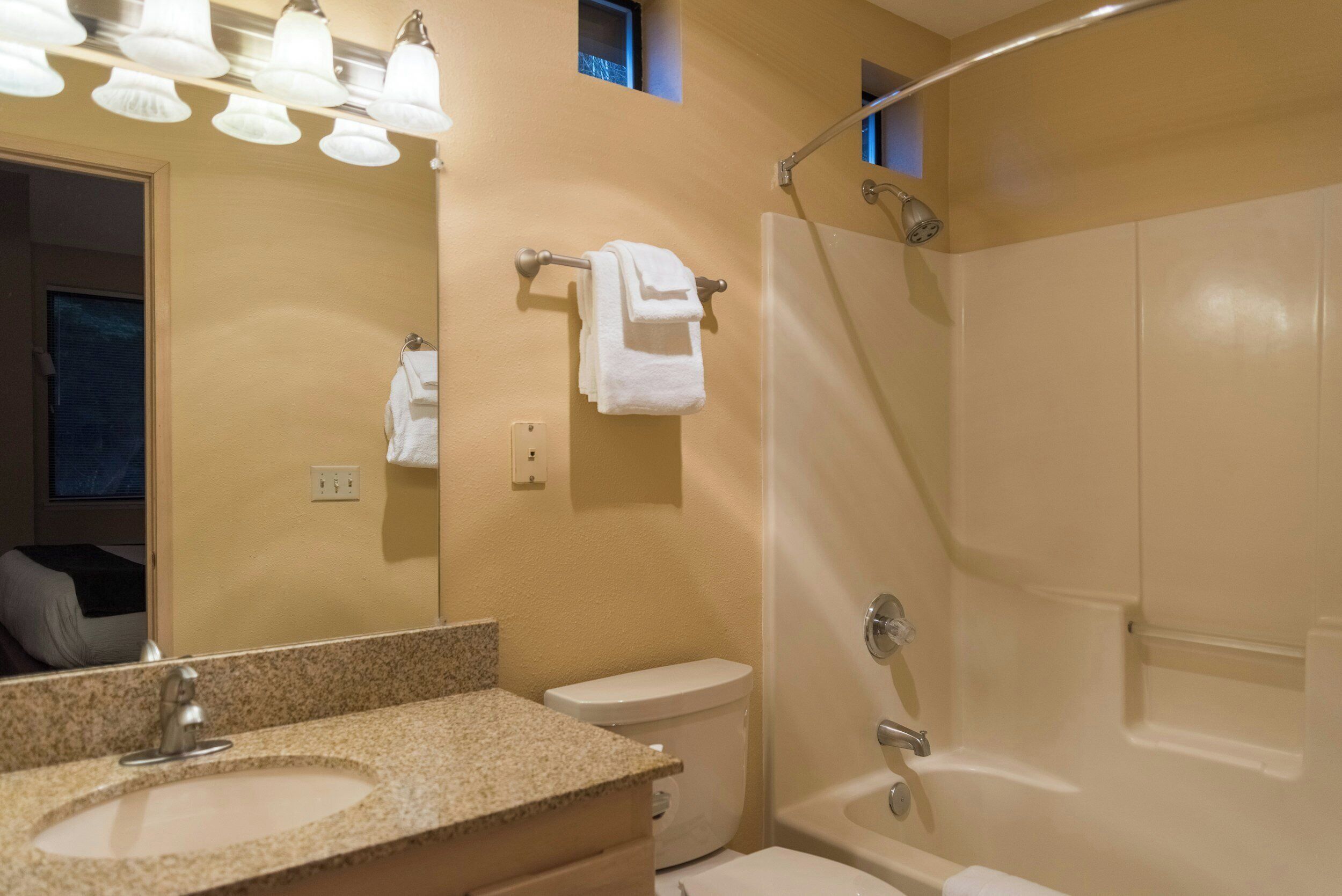 Une salle de bain avec un lavabo, des toilettes et une baignoire. Des serviettes sont suspendues sur un porte-serviettes et il y a une tringle pour le rideau de douche.