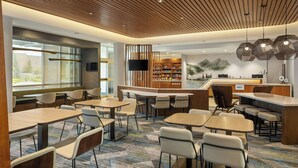 Un moderno vestíbulo de hotel con zonas de estar, un mostrador de recepción y una estantería.