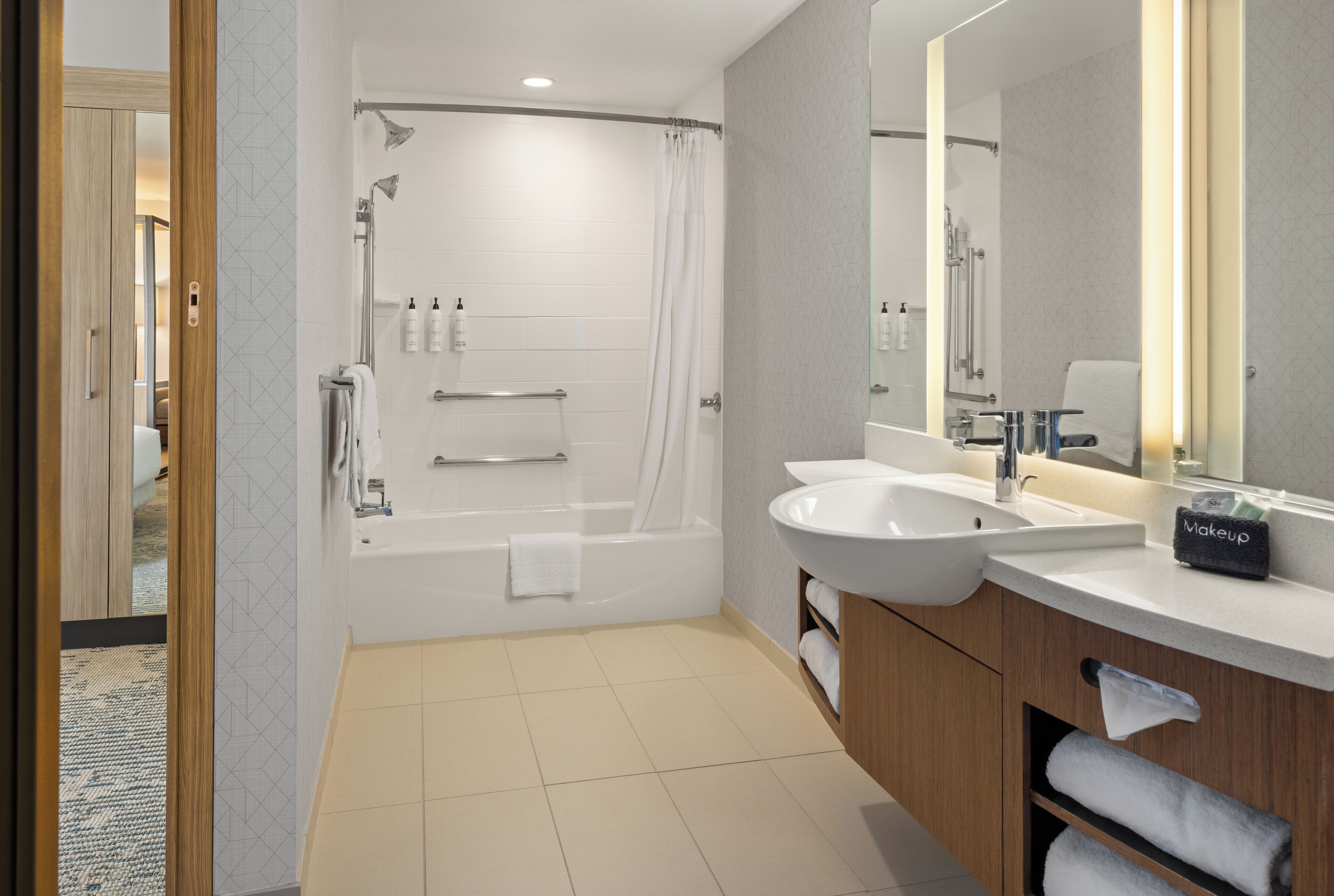 Un baño moderno con bañera, un espejo grande y un tocador con lavamanos.