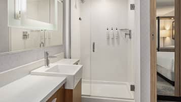 A modern bathroom with two sinks, a shower, and a mirror.