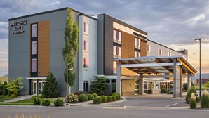 Un hotel moderno con entrada cubierta, un cartel de Springhill Suites Marriott y un jardín frontal ajardinado.