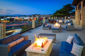 An outdoor seating area with wicker furniture, fire pits, and a view of the cityscape. - SpringHill Suites by Marriott The Dunes On Monterey Bay (Marina)