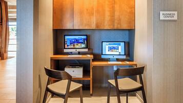 A business center with two Apple iMac computers, a printer, and two chairs.