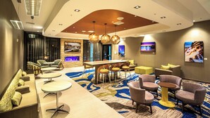 A modern hotel lobby with a curved ceiling, a bar area, seating arrangements, and artwork on the walls.