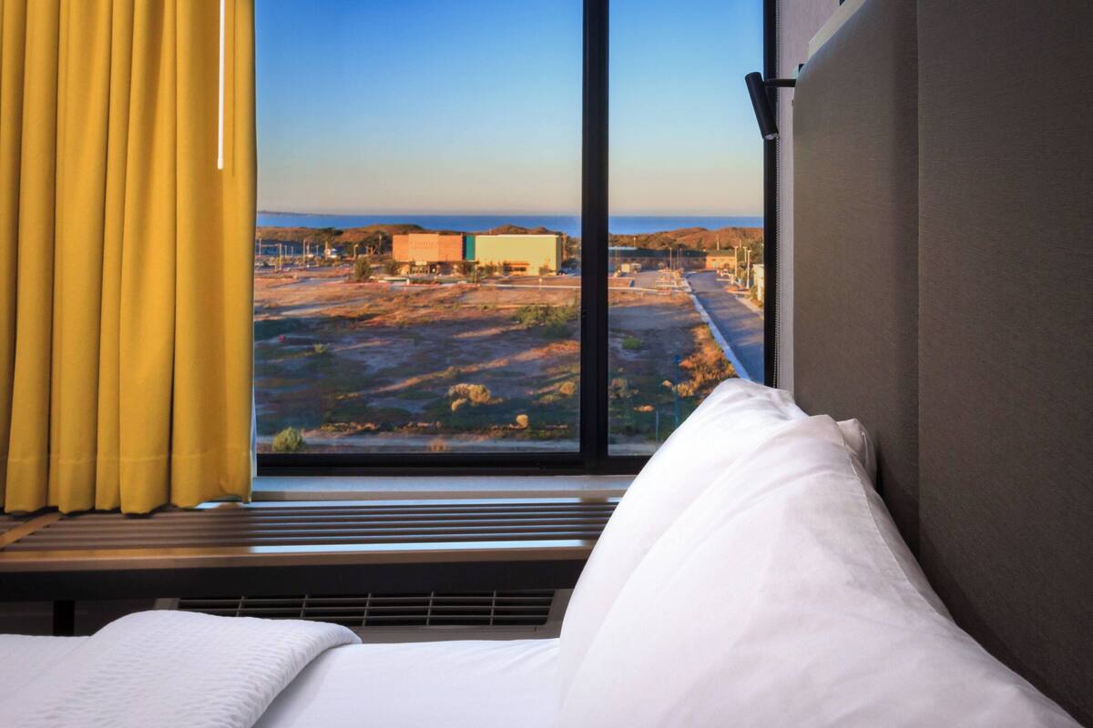 A hotel room with a large window offering a view of a distant landscape and buildings.