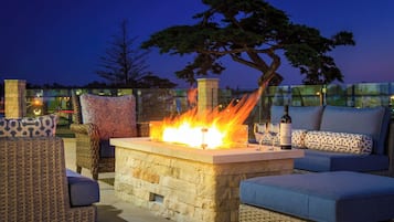 Relax in this serene outdoor seating area, surrounded by wicker furniture and a stone fire feature.