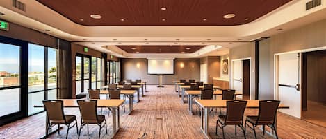 A conference room with a carpeted floor, wooden ceiling, and large windows.