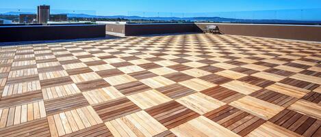Una terraza en la azotea con piso de madera a cuadros y vista despejada del paisaje urbano.