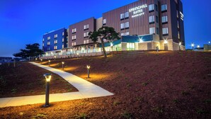 Um hotel moderno com telhado plano, vários andares e entrada bem iluminada.