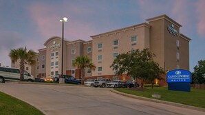 Un hôtel avec une enseigne indiquant « CANDLEWOOD SUITES » et un parking où sont stationnés plusieurs véhicules.