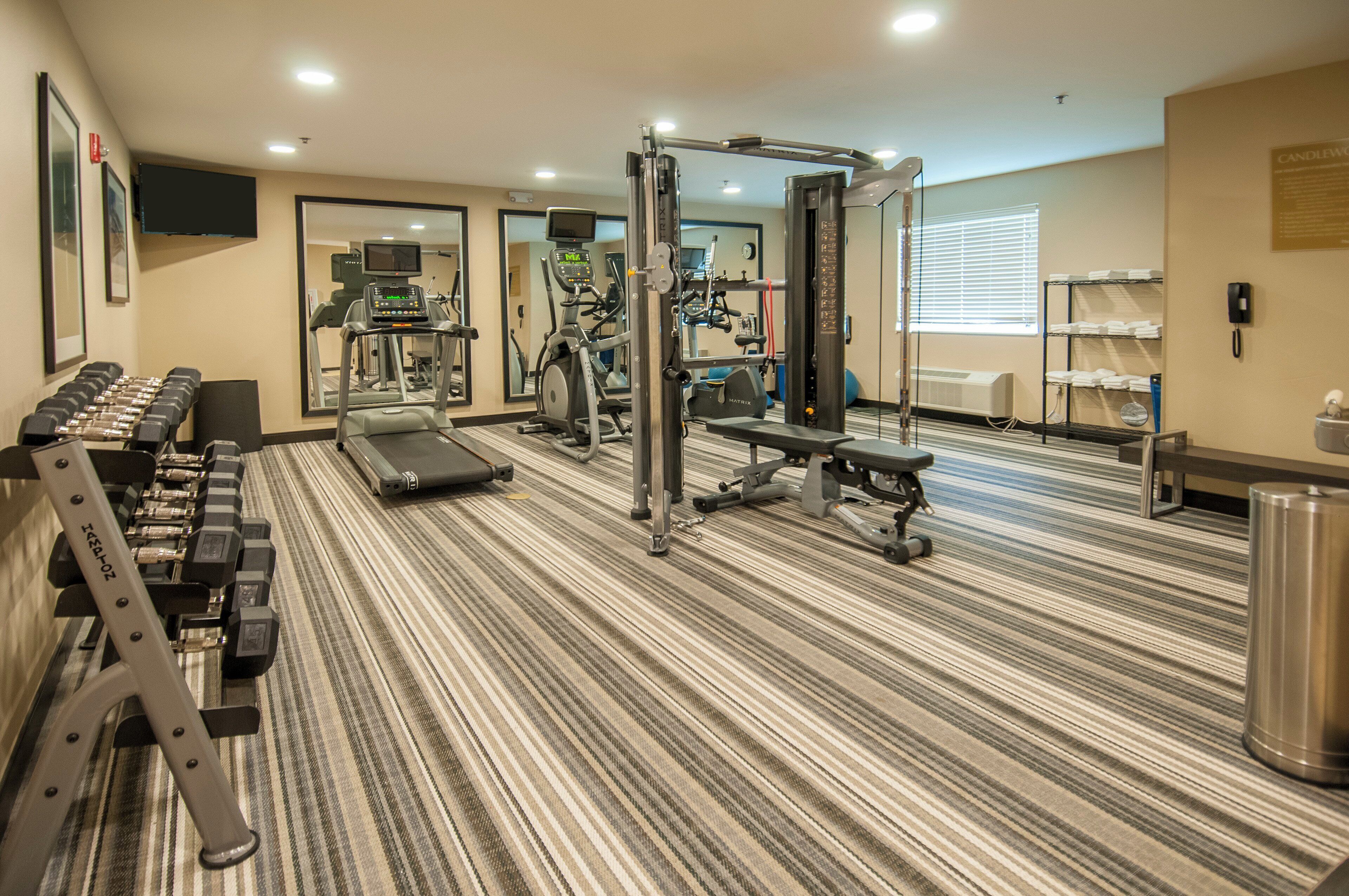 Un gimnasio hotelero con cintas de correr, máquinas de pesas y mancuernas.