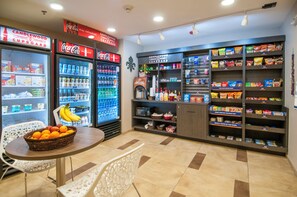 Ein Verkaufsstand für Snacks und Getränke mit Coca-Cola und Saft, einer Mikrowelle und einer Auswahl an Proviant.