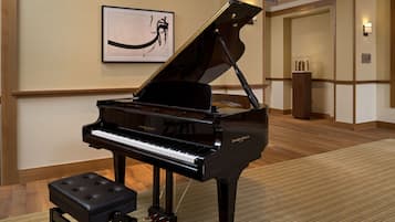 Un pianoforte a coda in un atrio di hotel, con un'opera incorniciata al muro e un podio in legno.