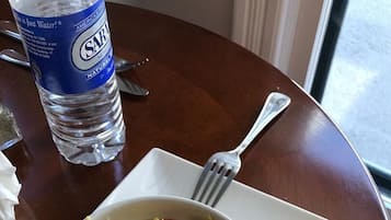 A breakfast plate with scrambled eggs, bacon, and green peppers, accompanied by a biscuit and a bottle of water.