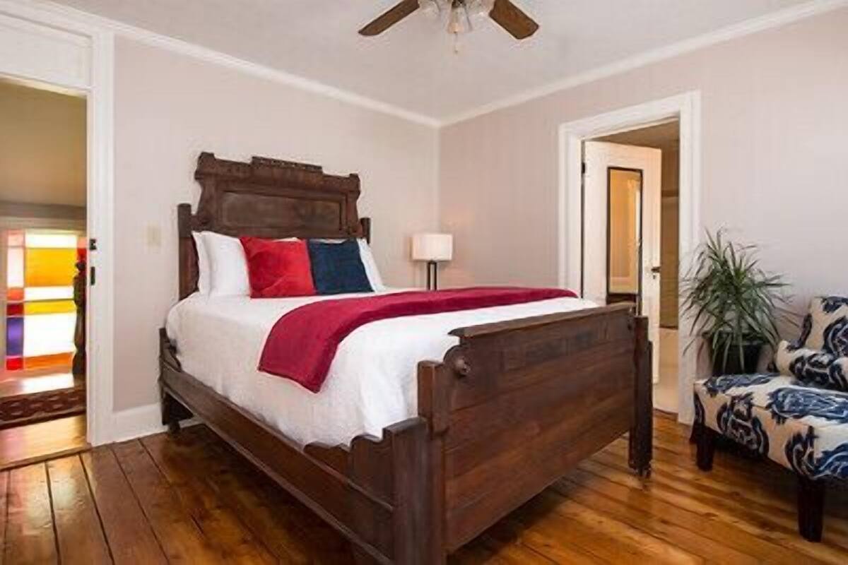 Ein Schlafzimmer mit einem Holzbett, einer roten Tagesdecke und einem Nachttisch mit einer Lampe.