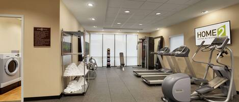 Un gimnasio de hotel con cintas de correr, una elíptica y una bicicleta estática.