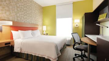 Habitación de hotel con cama, escritorio, silla y ventana con persianas.