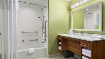 Un baño moderno con bañera, ducha, tocador y un espejo grande.