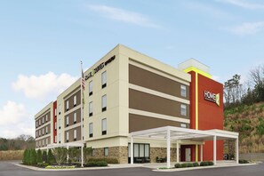 Un hotel de varios pisos con diseño moderno, que cuenta con una zona de estar cubierta al aire libre y un asta de bandera.