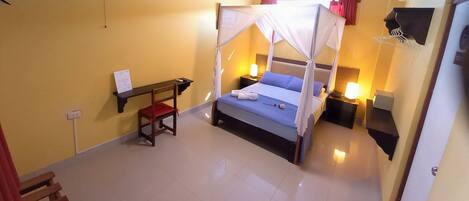 A bedroom with a bed under a canopy, bedside tables with lamps, a small desk, and a chair.