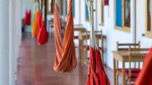 A corridor with hammocks hanging from the ceiling, wooden tables, and chairs along the walls. - Mancora y Sol (Máncora)