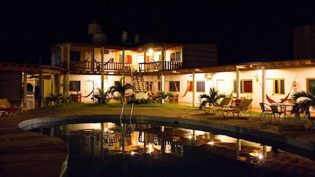 A two-story building with a swimming pool, outdoor seating, and a staircase leading to the upper floor. - Mancora y Sol (Máncora)
