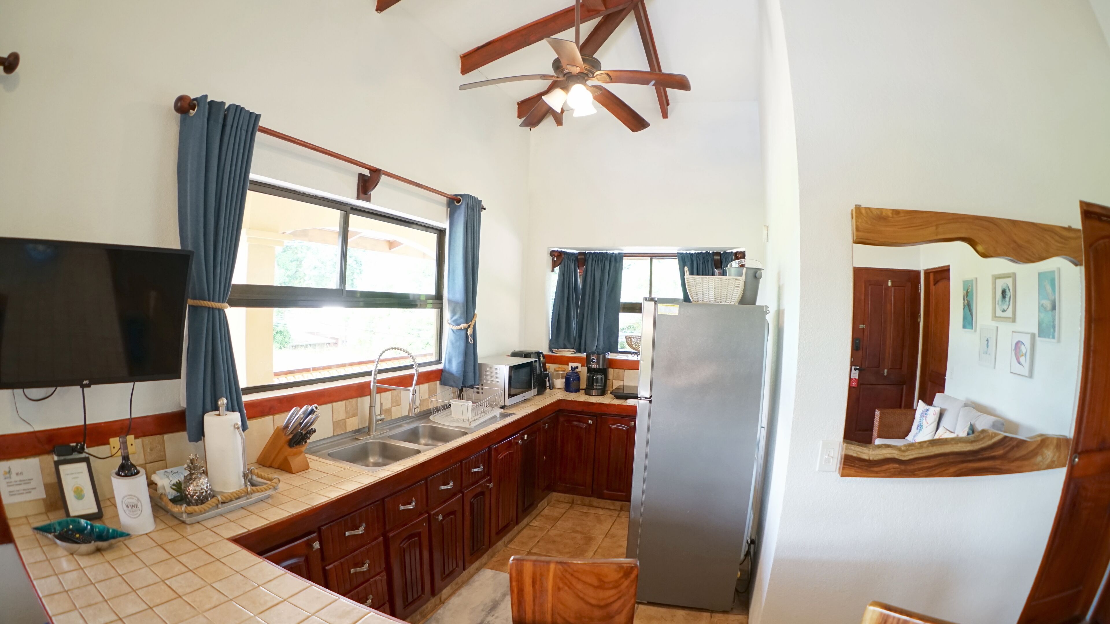 A compact kitchen with a large window, a ceiling fan, and a refrigerator.
