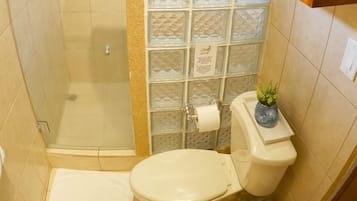 A bathroom with a shower, toilet, and a cabinet with towels.
