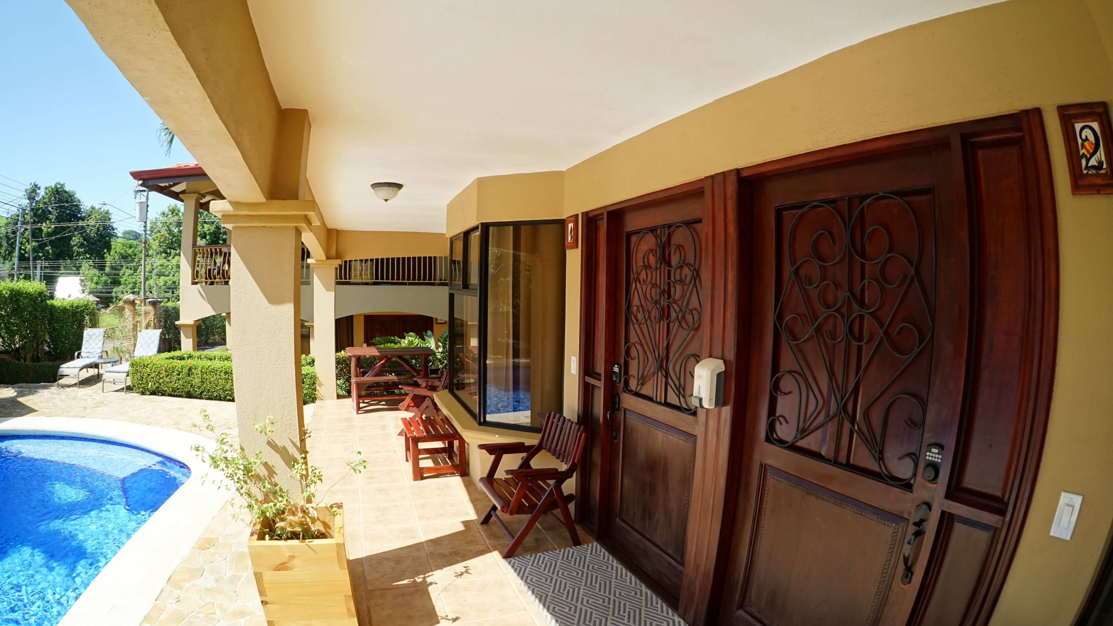 A poolside area with a wooden bench, a table, and a door with intricate metalwork.