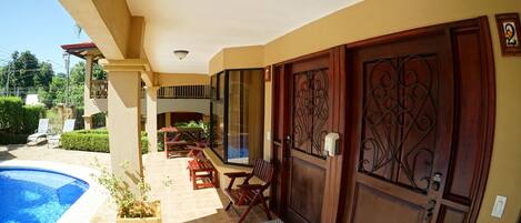 A poolside area with a wooden bench, a table, and a door with intricate metalwork.