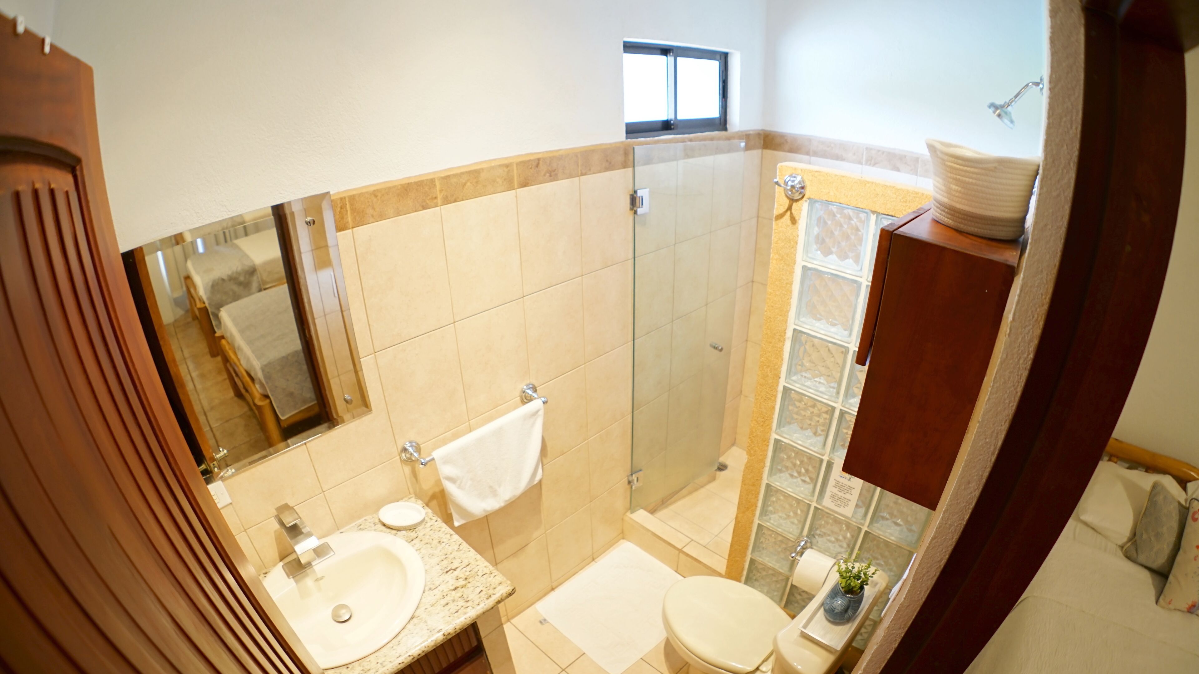 A bathroom with a sink, mirror, towel rack, toilet, and a glass shower enclosure.
