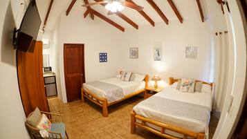 Una habitación con dos camas de madera, una mesita, una silla y un televisor montado en la pared.