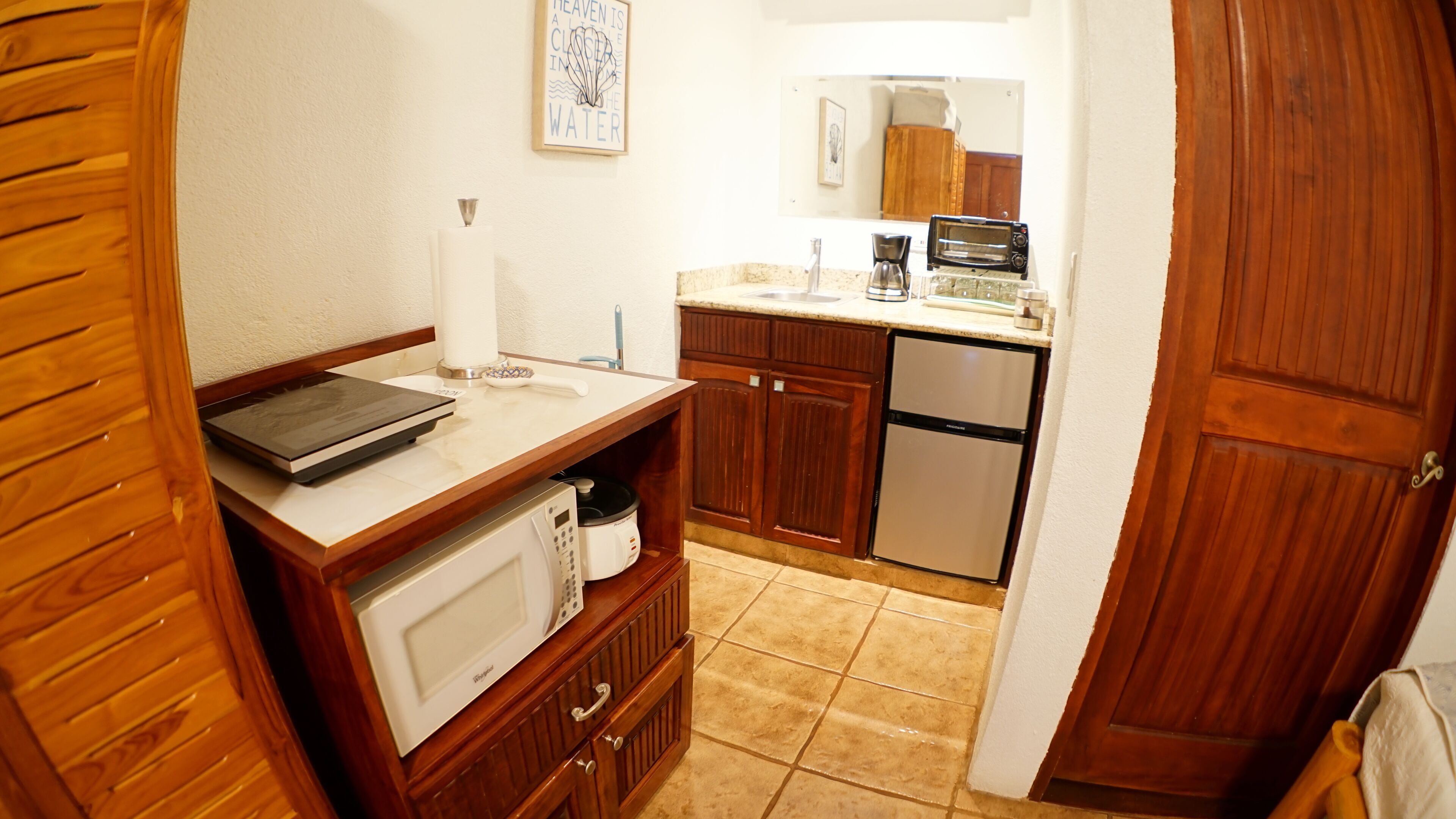 A compact kitchen with wooden cabinets, a microwave, a toaster, and a coffee maker.