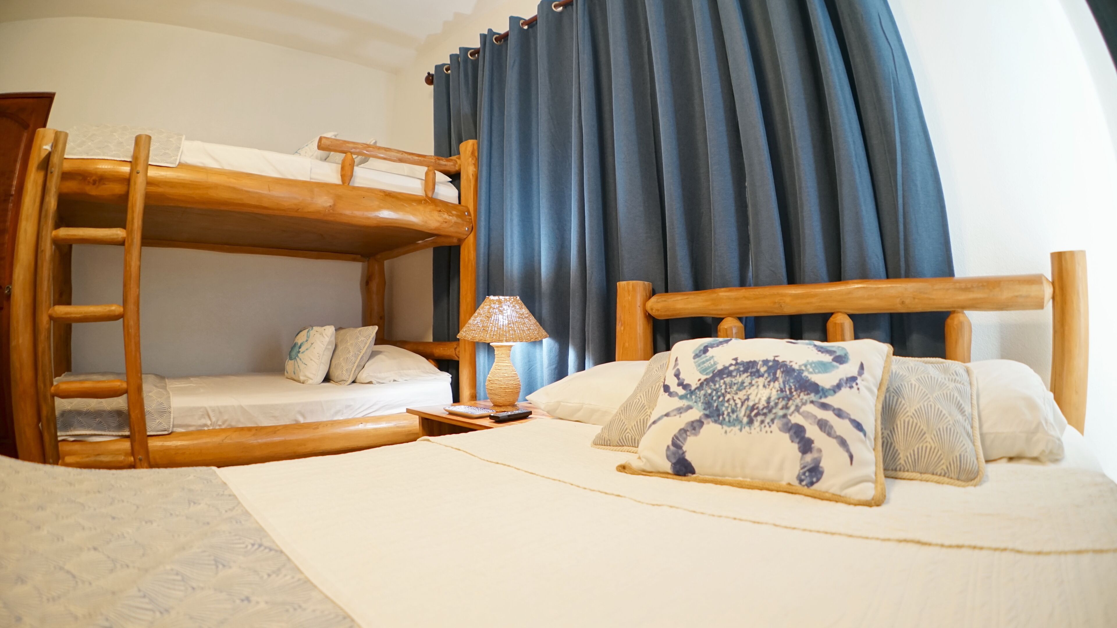 Una camera con un letto a castello, una scala in legno, un comodino con una lampada e un letto con cuscini decorati.