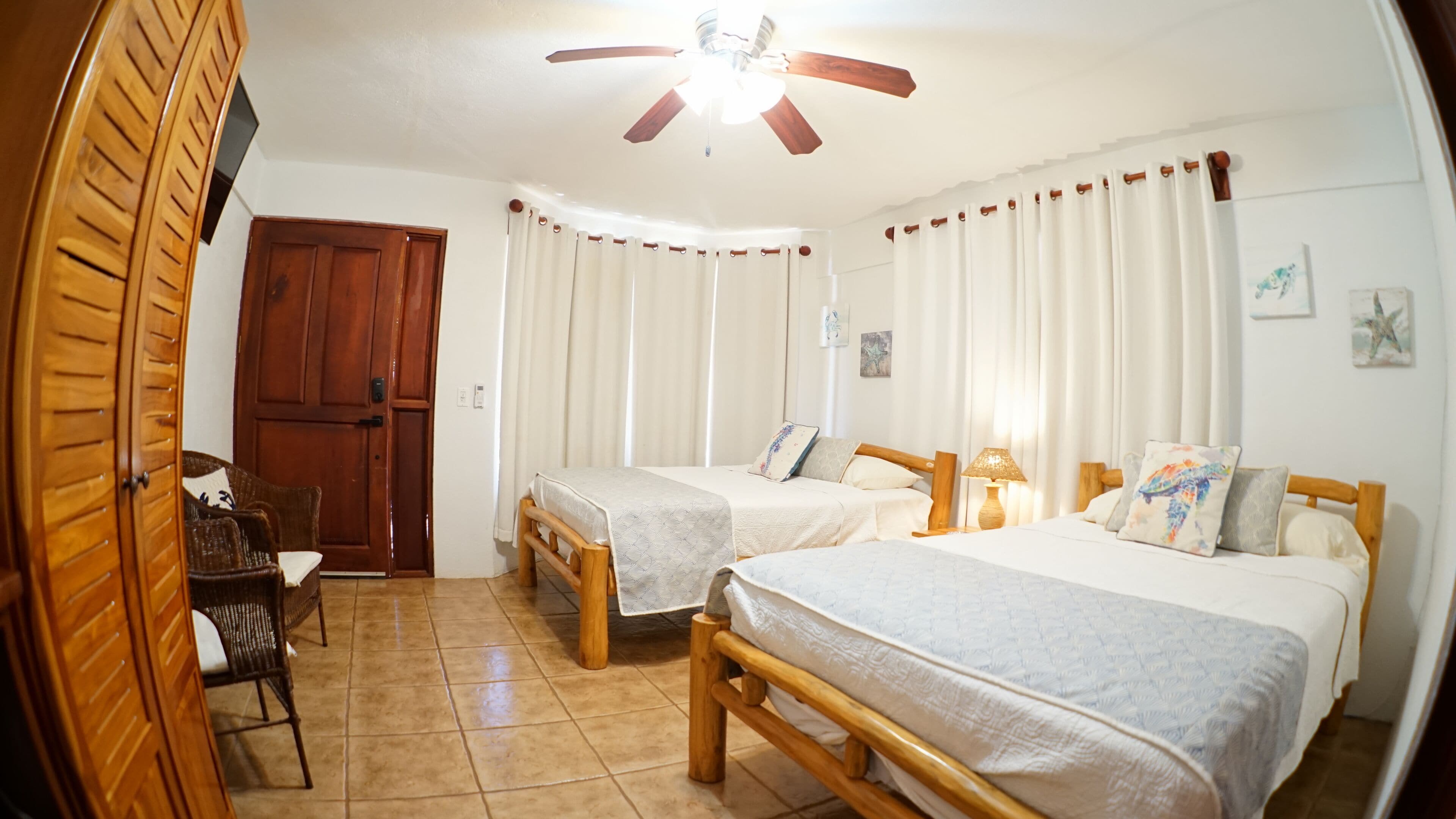 Una habitación con dos camas de madera, un armario de madera, una silla y un ventilador de techo.