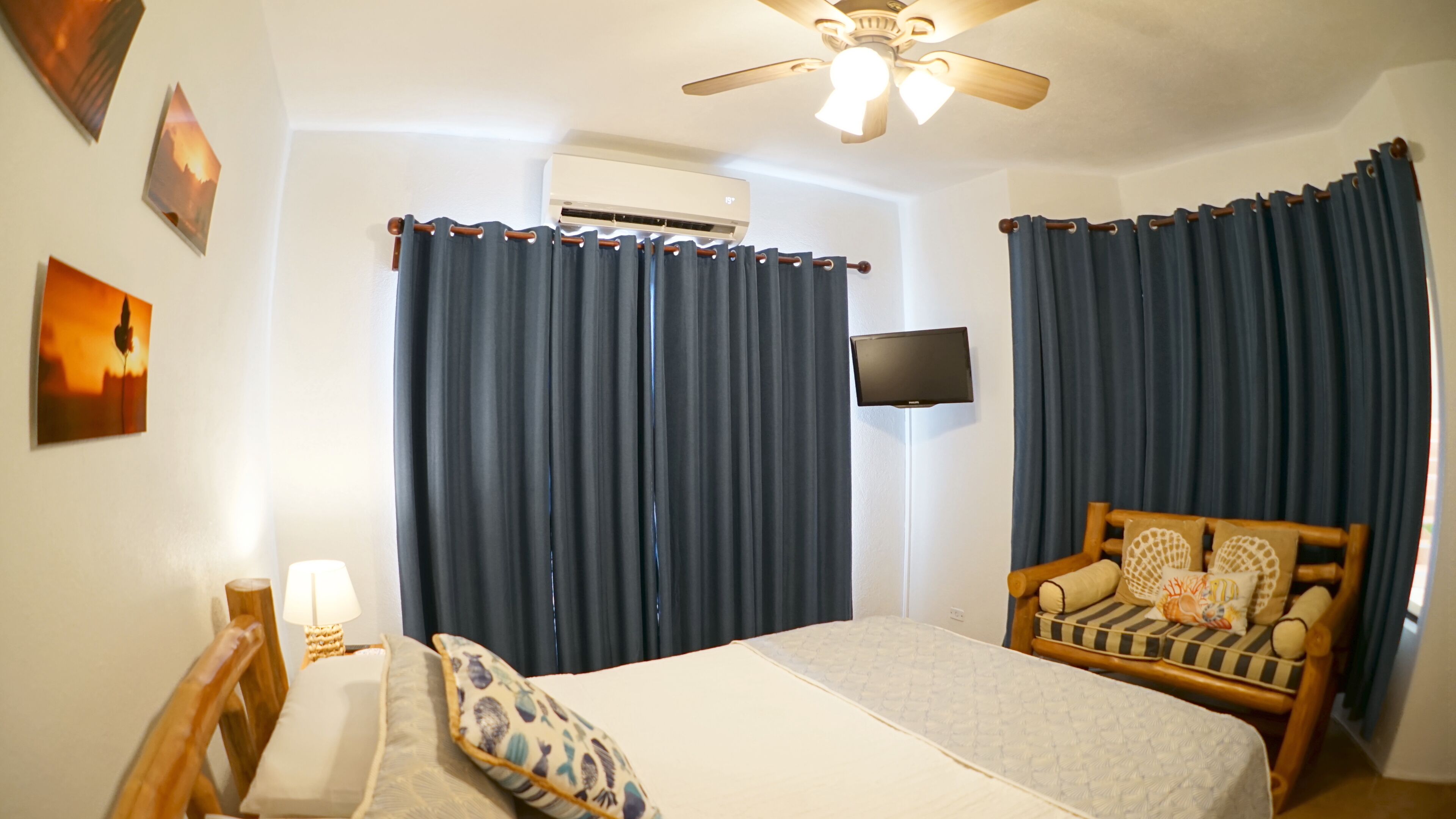 A bedroom with a bed, a wooden chair, a TV, and curtains.
