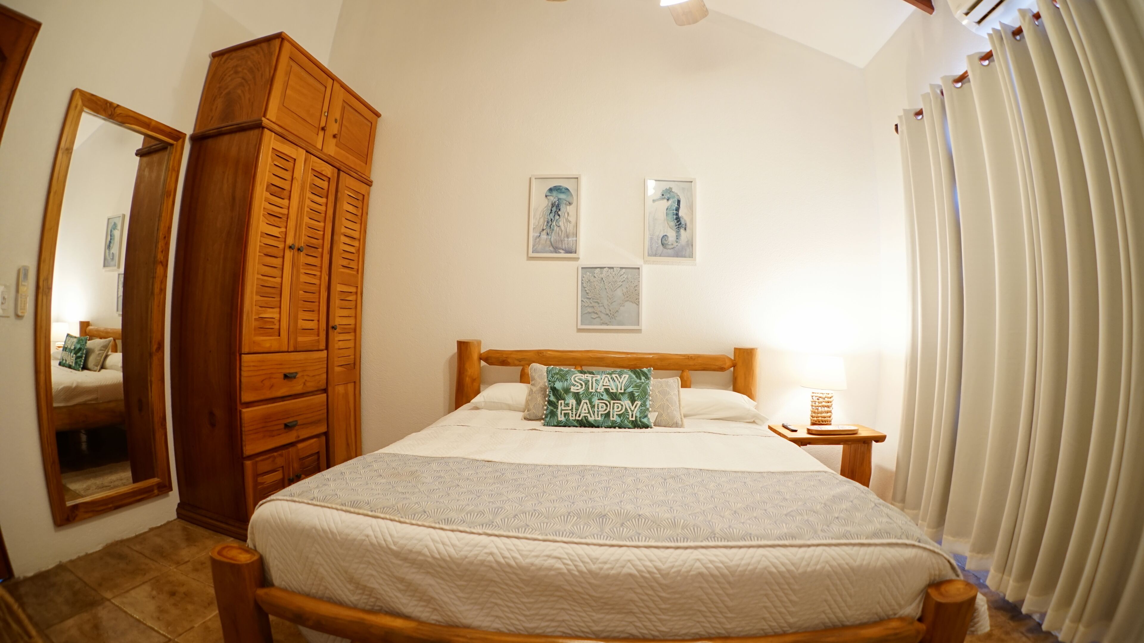 A bedroom with a wooden bed, a wardrobe, a bedside table with a lamp, and a window with curtains.