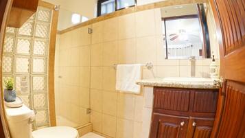 A bathroom with a toilet, shower, and sink.