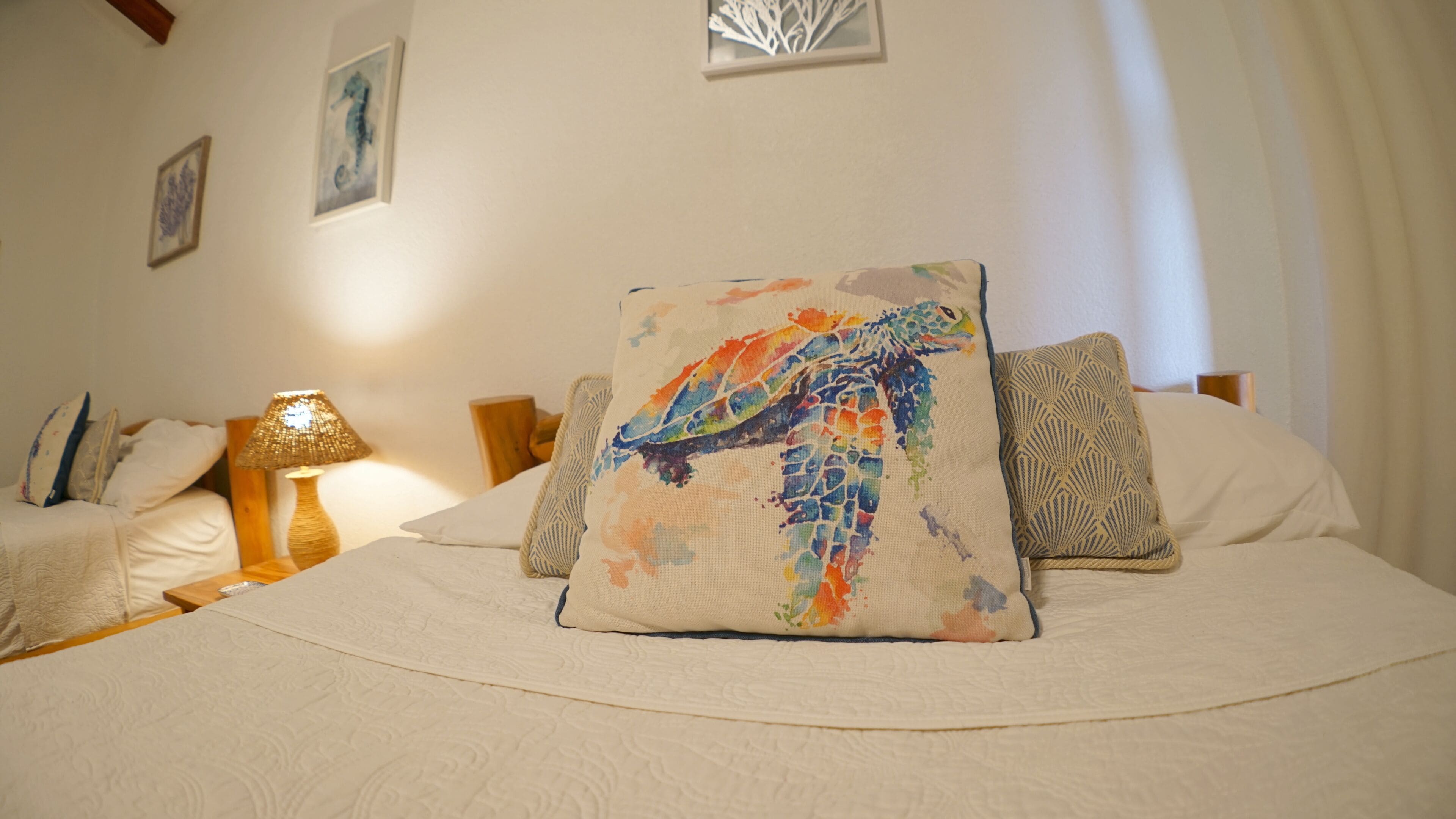 A hotel room with a bed, two bedside tables, a lamp, and decorative pillows.
