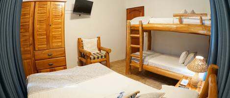 A room with bunk beds, a wooden wardrobe, a chair, a television, and a bedside lamp.