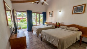A hotel room with two beds, a wooden desk, a ceiling fan, and a view of the outdoors. - Guanacaste Lodge (Cabo Velas)