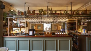 A bar area with a counter, shelves of bottles, and hanging glasses. - Methuen Arms (Corsham)