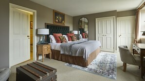 A bedroom with a large bed, a dresser, a desk, and a chair. There is a mirror on the wall and a picture above the bed. - Methuen Arms (Corsham)