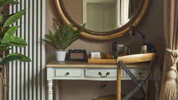 A room with a wooden chair, a white desk, a large mirror, a radiator, a potted plant, and a curtain.