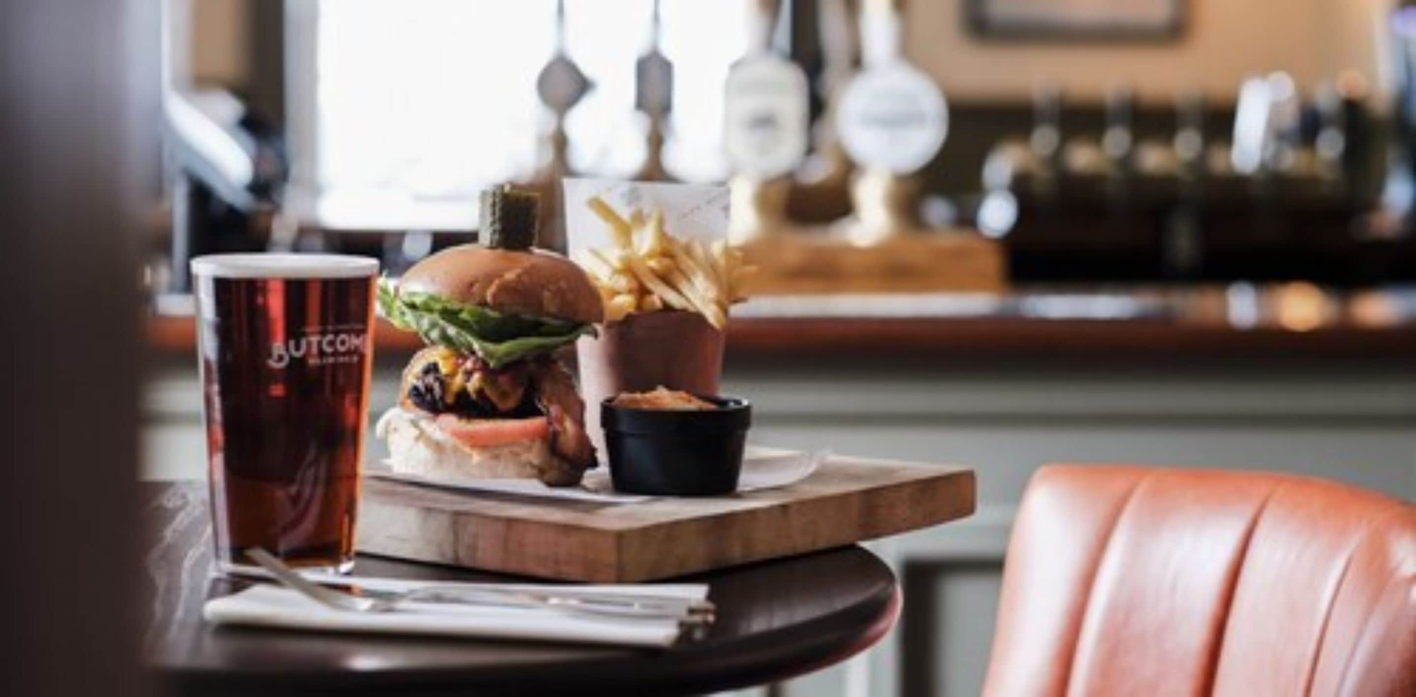 Un repas composé d’un hamburger, de frites et d’une boisson, servi sur une table en bois dans un restaurant.