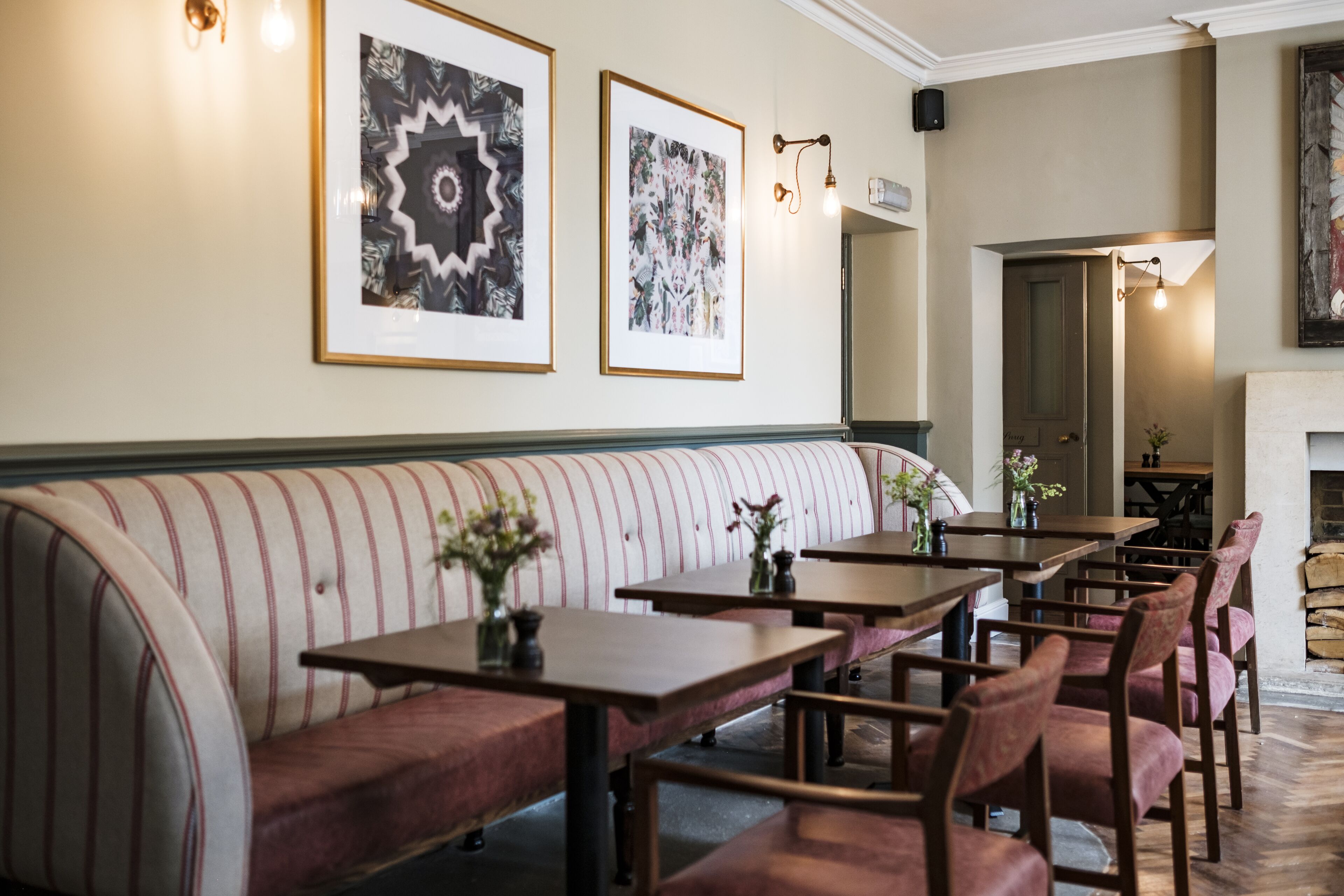 A restaurant with a long bench seating area, tables, and chairs.